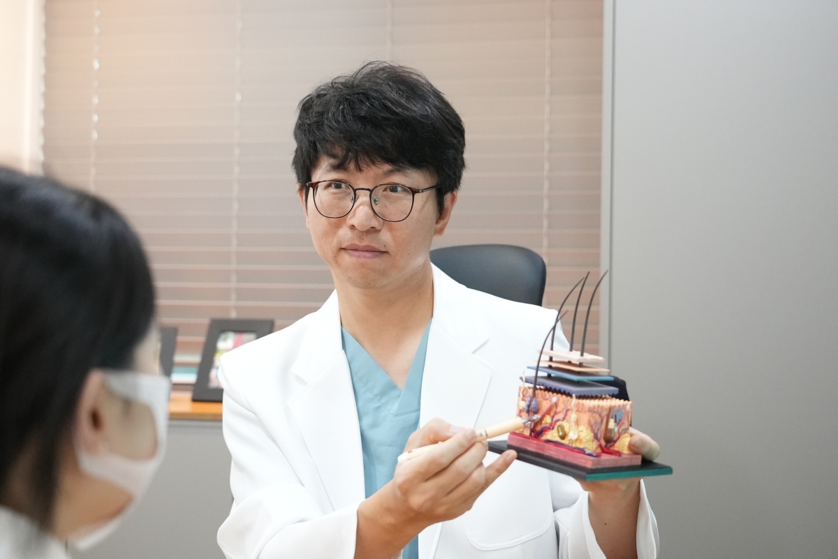 신도림점 이신기 대표원장이 피부 모형으로 피지샘과 피부 염증의 관계를 설명합니다.